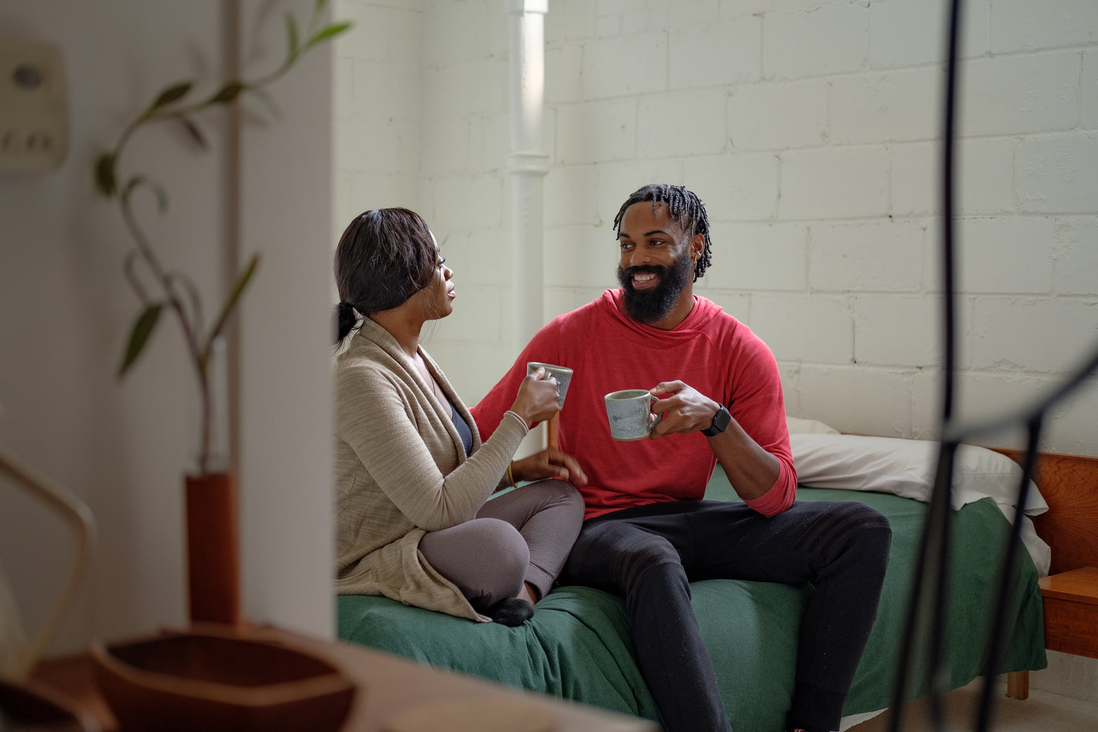A couple relaxing together in bed with coffee